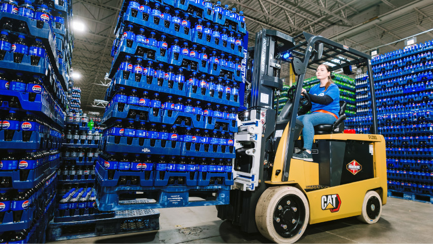 Woman on forklift moving product around in warehouse