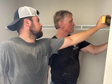 2 men measuring an area in a closet