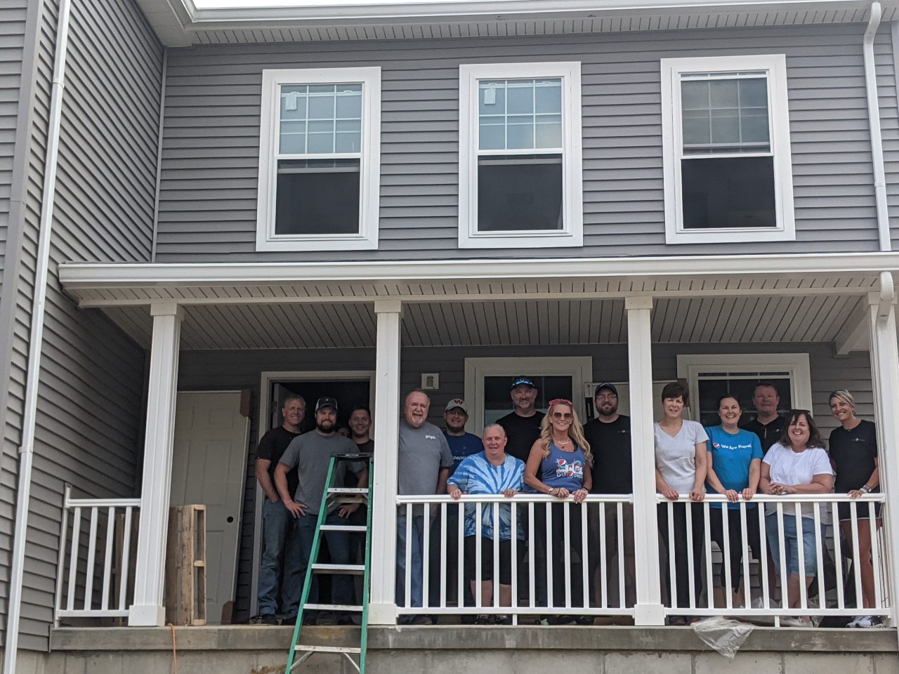 team members posing in front of home